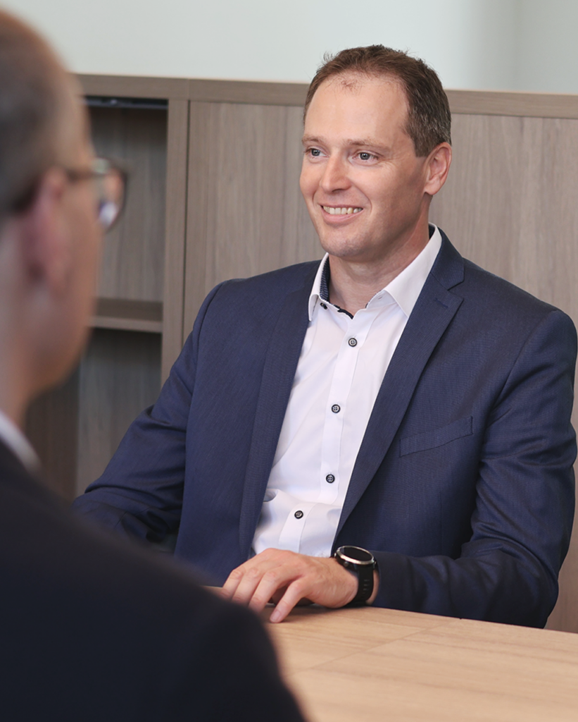 Consolv Steuerberatung - Partner Peter Dorn lächelt und sitzt an Besprechungstisch